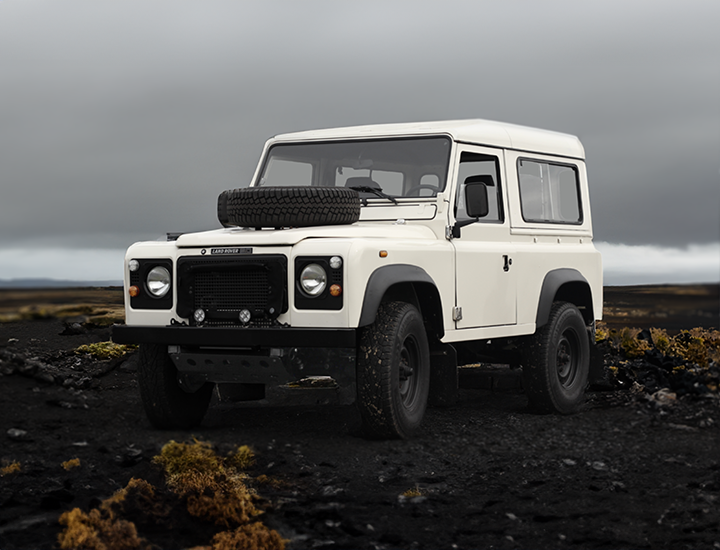 weißer restaurierter Land Rover Defender 90 in rauer Landschaft Island Moss und Gestein