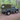 Land Rover Defender 90 mit Soft Top Verdeck in oliv grün aus Canvas im Wald. Im Hintergrund sind Bäume zu sehen. Das Verdeck hat ein Heckfenster.